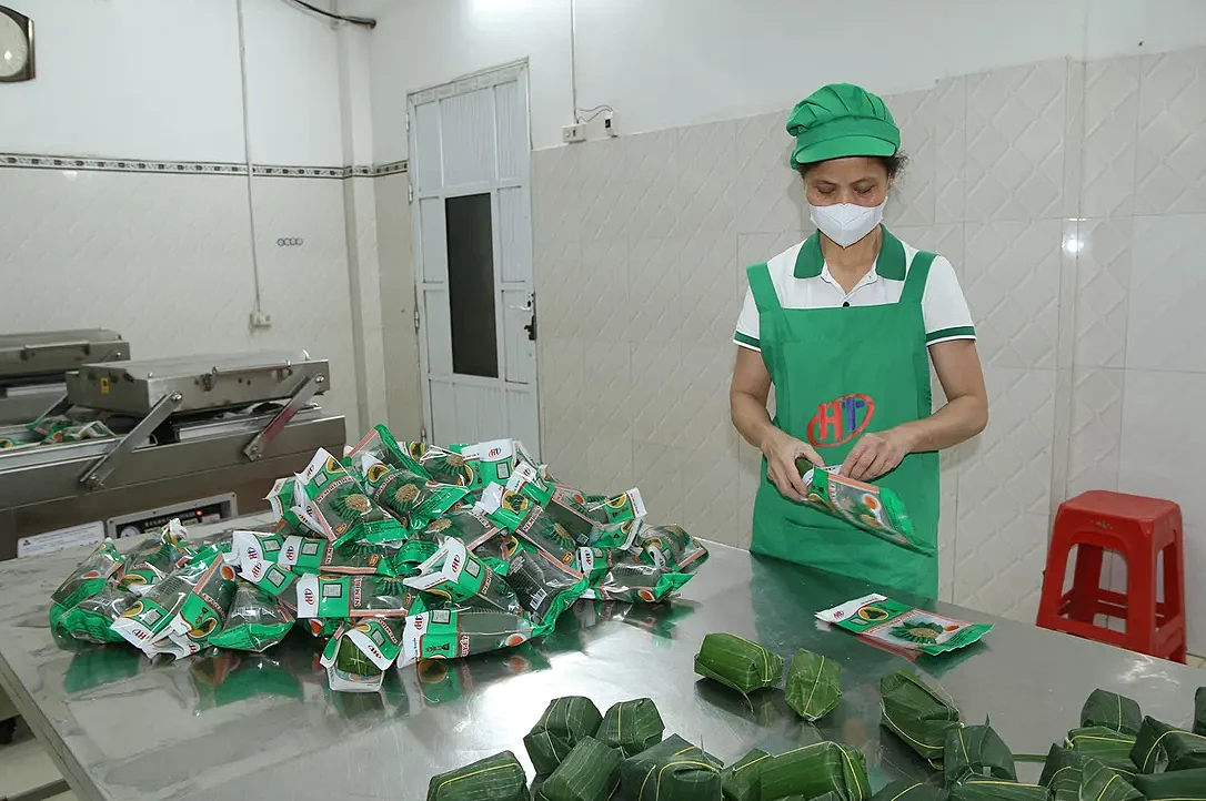 Nhân viên cơ sở Hải Tuyết đóng gói nem; phía trước là những gói nem bọc lá chuối