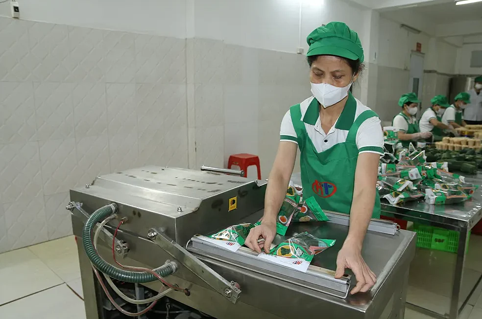 Nhân viên đặt các gói nem vào máy hút chân không
