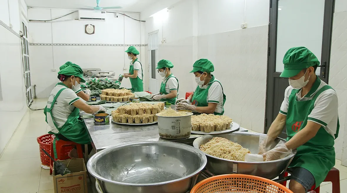 Nhân viên đội mũ, đeo khẩu trang và găng tay trộn nem với thính trong xưởng